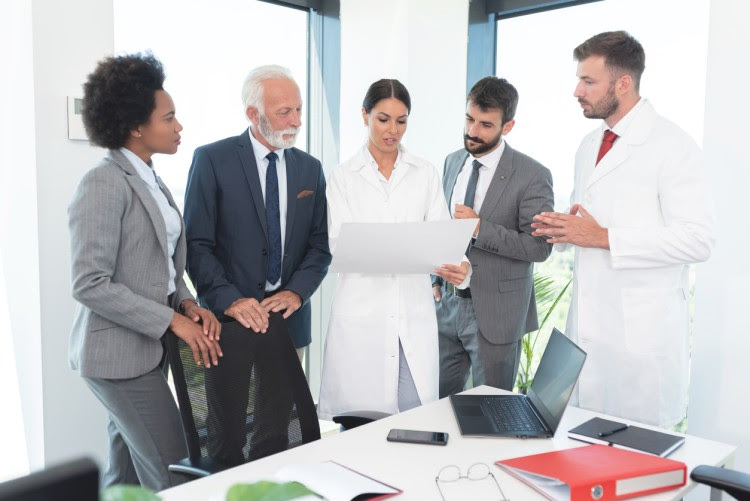 Healthcare leaders meet around a conference table in a hospital.