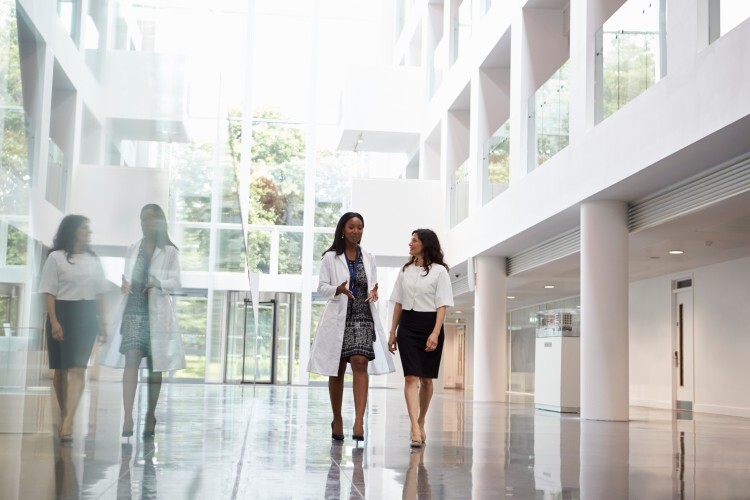 A hospital administrator talks to a physician while walking down a hospital hallway.