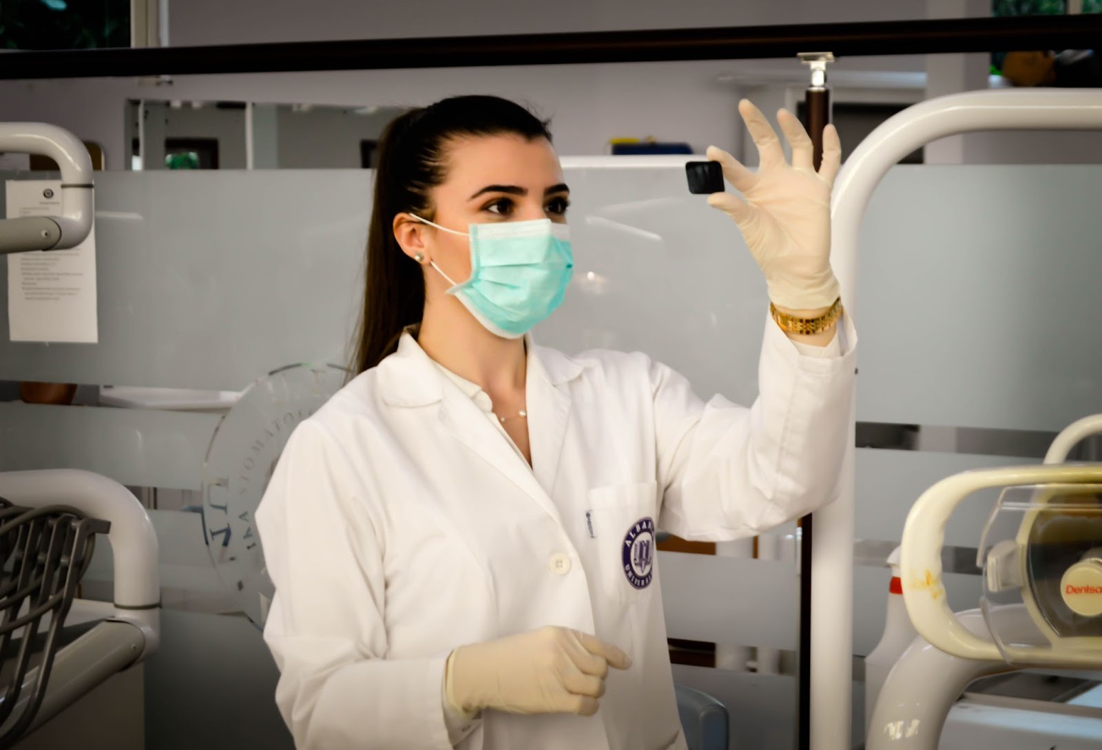 A female medical professional wears a white lab coat while looking at radiographic film.