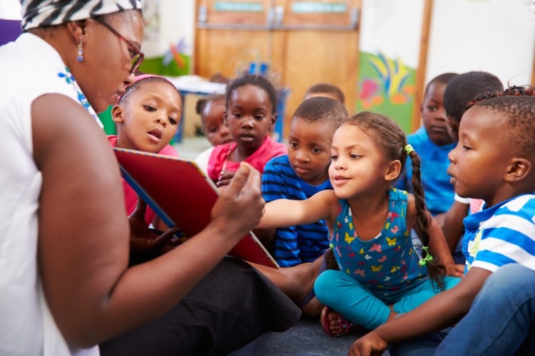 A teacher reads a story to young students.