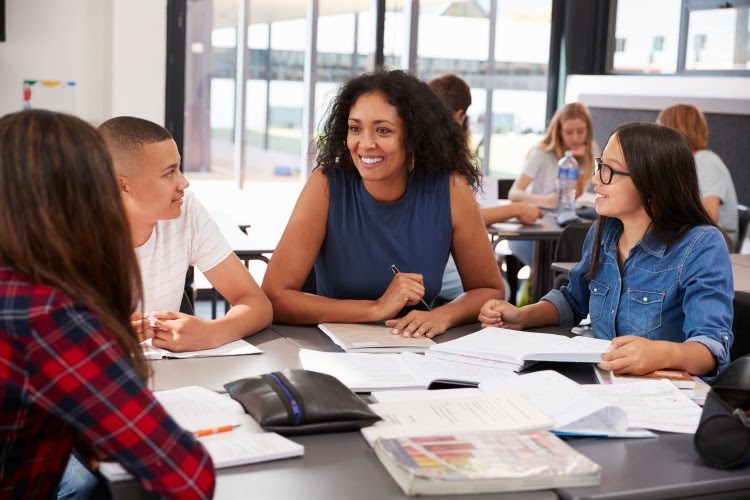 A teacher helps a group of high school students studying together.