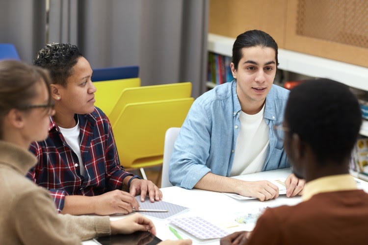 A group of high school students sits in a circle having a conversation.