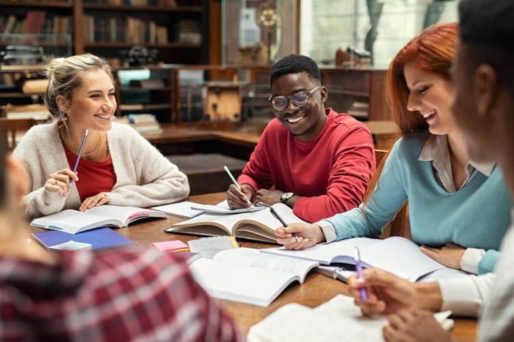 A group of high school students study together in a library.