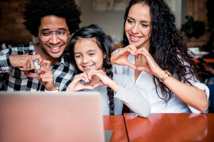 A family of three has a video chat with a teacher.