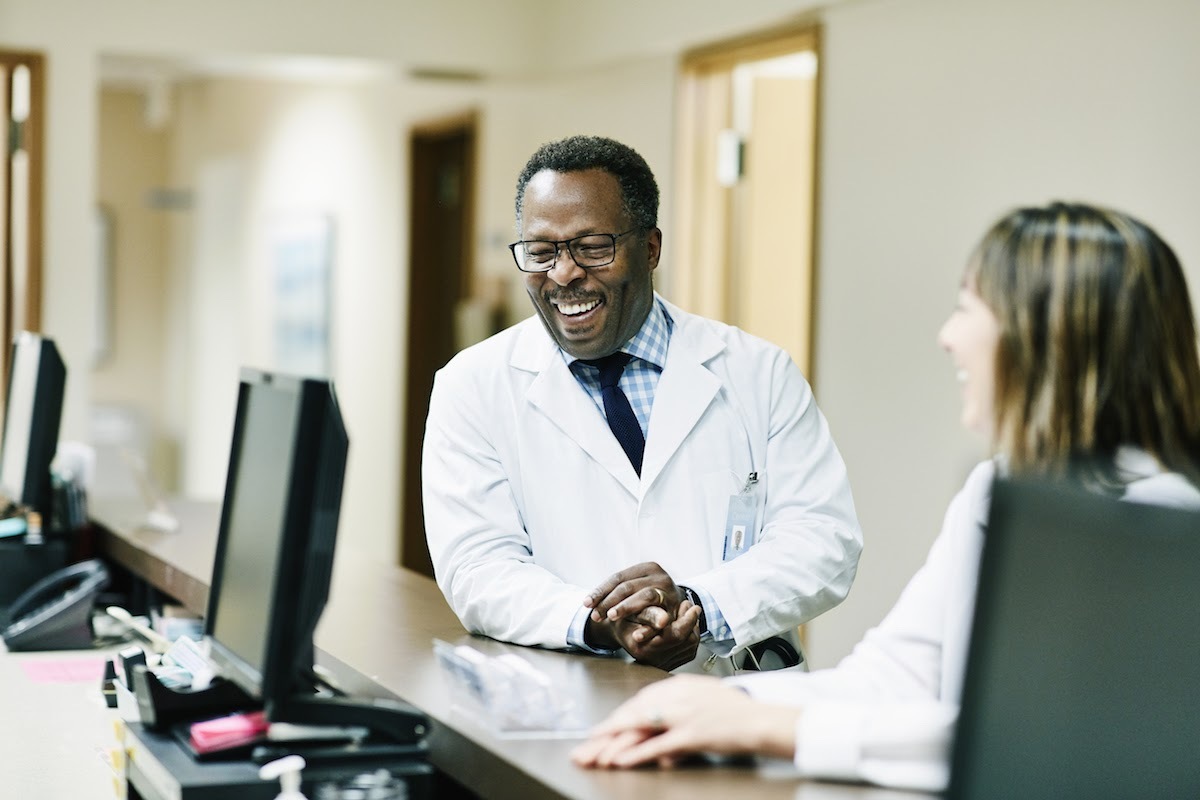 Healthcare management professionals show interpersonal skills, laughing together in a healthcare facility.