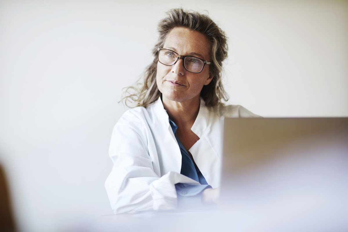 A female healthcare manager works on a laptop computer.